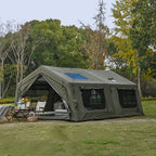Large green canvas camping tent set up outdoors with folding chairs and picnic table