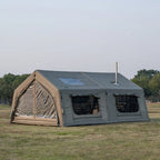 Large canvas camping tent with windows and stove jack set up on grassy field outdoors