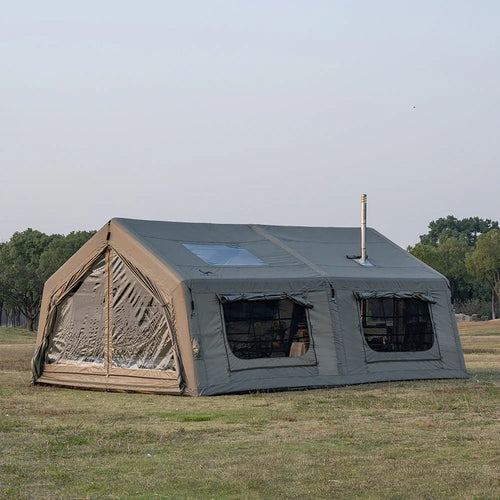 Large canvas camping tent with windows and stove jack set up on grassy field outdoors