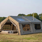 Large canvas wall tent with stove jack, mesh windows, and outdoor camping setup on grass