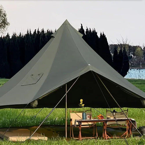 Large green canvas camping tent set up on grass with chairs and table outdoors