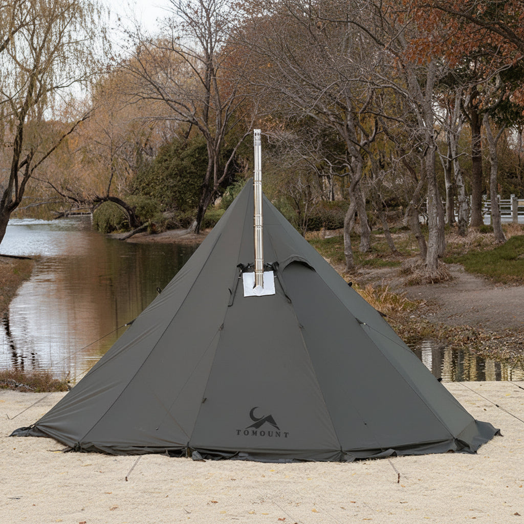 Large green teepee camping tent with stove jack by a river in a forested area